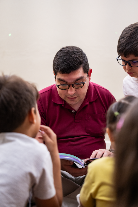 Professor lendo um livro para crianças sentadas ao seu redor